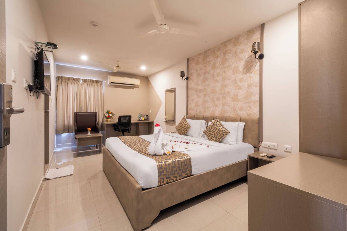 A hotel room with a large bed, bedside tables, a desk, and a chair.