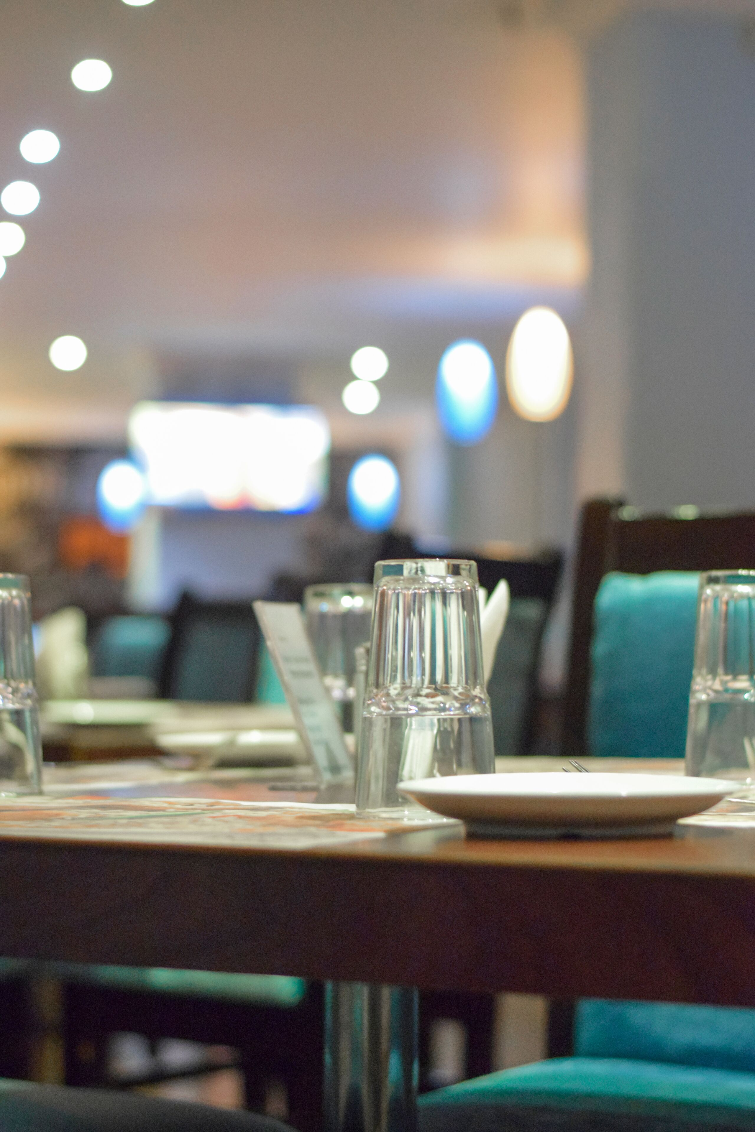 A restaurant setting with tables set for dining, glasses, and a menu.