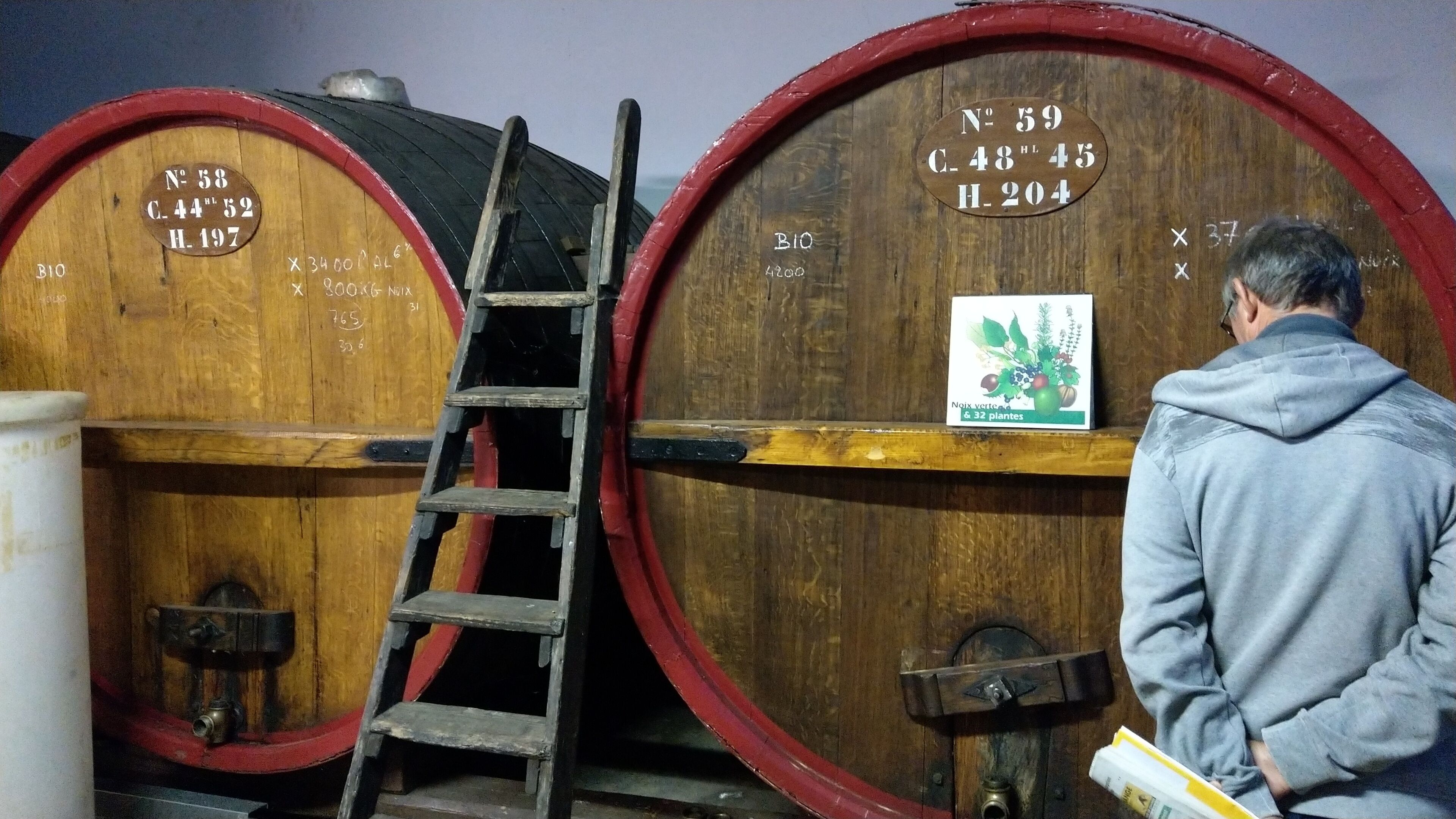 Deux barils en bois, chacun portant une étiquette, une échelle et une personne debout devant.