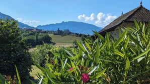 A rural landscape with a stone building, lush greenery, and distant mountains. - Vacation rental lakes, vineyards and mountains area (MASSIGNIEU DE RIVES)