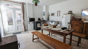 A kitchen with a wooden table set for dining, a microwave, a refrigerator, and a bench. - Vacation rental lakes, vineyards and mountains area (MASSIGNIEU DE RIVES)