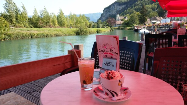 A table with a drink and dessert, overlooking a river with boats and a church in the background. - Vacation rental lakes, vineyards and mountains area (MASSIGNIEU DE RIVES)