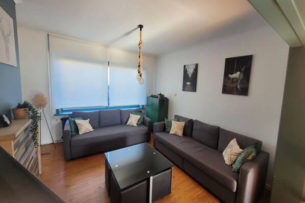 A modern living room with two sofas, a coffee table, and a hanging light fixture.