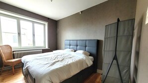A bedroom with a bed, a chair, a window, and a radiator. - Holiday home in Zuienkerke with a terrace (Zuienkerke)