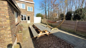 A backyard with a wooden deck, a hammock, and a picnic table. - Holiday home in Zuienkerke with a terrace (Zuienkerke)