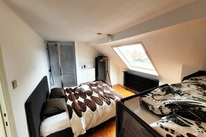 A compact bedroom with a bed, a wardrobe, and a skylight.