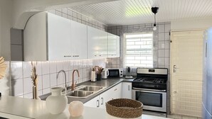 Una cucina moderna con mobili bianchi, un lavello in acciaio inox, un piano cottura a gas e una finestra che offre luce naturale.