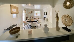 Un'area pranzo moderna con un tavolo rotondo, sedie bianche e un bancone bianco decorato.