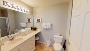 Un baño con un espejo grande, un lavabo, un inodoro y dos cuadros en la pared.