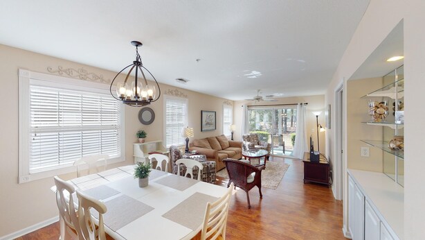 A spacious living area with a dining table, chairs, a sofa, and a chandelier. - Golf Course Oasis Inviting 3BRVilla Pawleys Island (Pawleys Island)