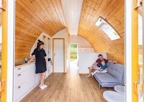 A cozy interior with wooden walls, a kitchenette, a sofa, and a door leading outside.