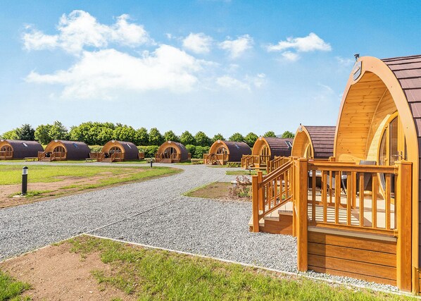 A row of wooden dome-shaped cabins with a gravel path leading to them.