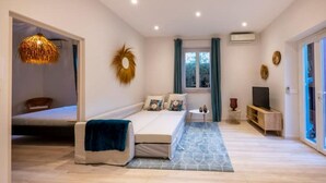 A modern bedroom with a bed, a small table, a TV, and a window with curtains. - Sublime 2 Pièces Avec Jardin (Villefranche-sur-Mer)