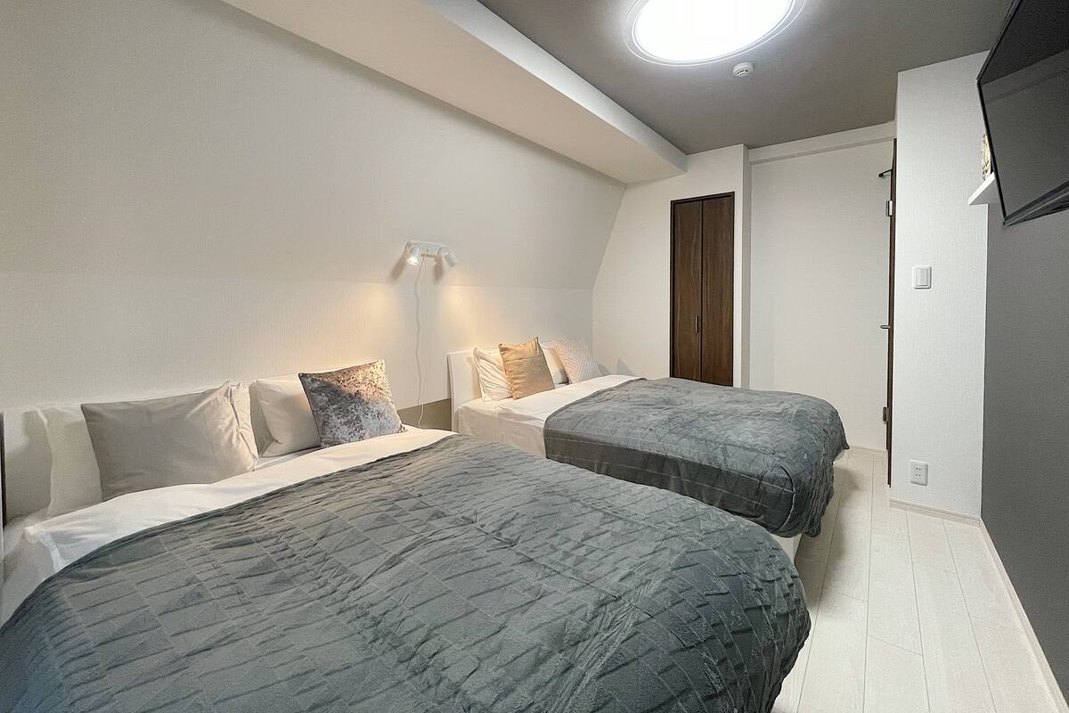 A bedroom with two beds, a wardrobe, and a ceiling light.