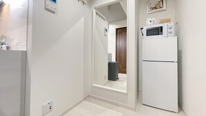 Ein Gang mit einem weißen Kühlschrank, einer Mikrowelle darauf und einer Tür zu einem anderen Raum.