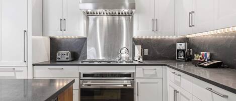 A modern kitchen with white cabinets, stainless steel appliances, and a black countertop.