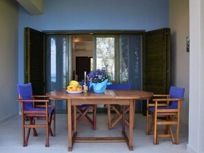 A dining area with a wooden table and four blue chairs, a bowl of fruit, and a vase of flowers.
