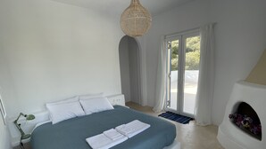 Un dormitorio con cama, lámpara de noche, ventana con cortinas y chimenea decorada con flores.