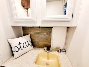 A bathroom with a stone backsplash, a sink, and a towel rack. - 34ft Mobile Home Near Yale U (New Haven)