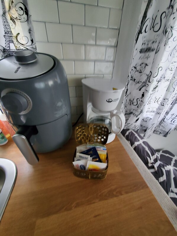 Una cocina con cafetera, hervidor y jarra de café sobre la encimera.
