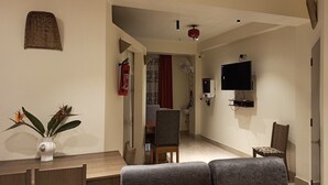 Un salon moderne comprenant un coin repas, un téléviseur à écran plat fixé au mur et un ventilateur de plafond.