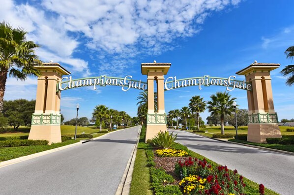 Une route menant à une entrée fermée par un portail, sur laquelle on peut lire l’inscription « ChampionsGate ».