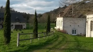 A rural property with a fenced pathway leading to a white building with columns, surrounded by greenery and trees. - Harcourt priory (Harcourt)