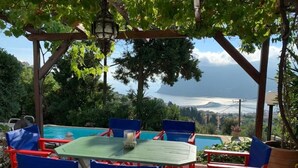 Un espace aménagé au bord de la piscine, avec une table et des chaises, une pergola et une vue sur la mer.