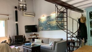 Un salon avec un canapé, un téléviseur, un escalier et un tableau accroché au mur.