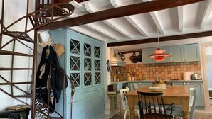 Un coin repas avec une table et des chaises en bois, un buffet bleu et un escalier.