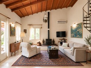 A living room with a fireplace, sofa, TV, and a large window.