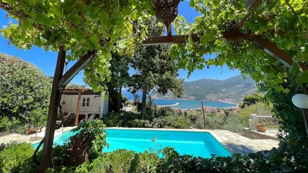 Une piscine entourée d’une végétation luxuriante, avec vue sur un lac et des montagnes.