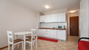 Une cuisine de taille réduite avec des meubles blancs, une petite table à manger et des chaises.