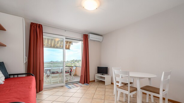 Une chambre d’hôtel comprenant un lit, une télévision, une table à manger avec des chaises et un balcon avec vue.