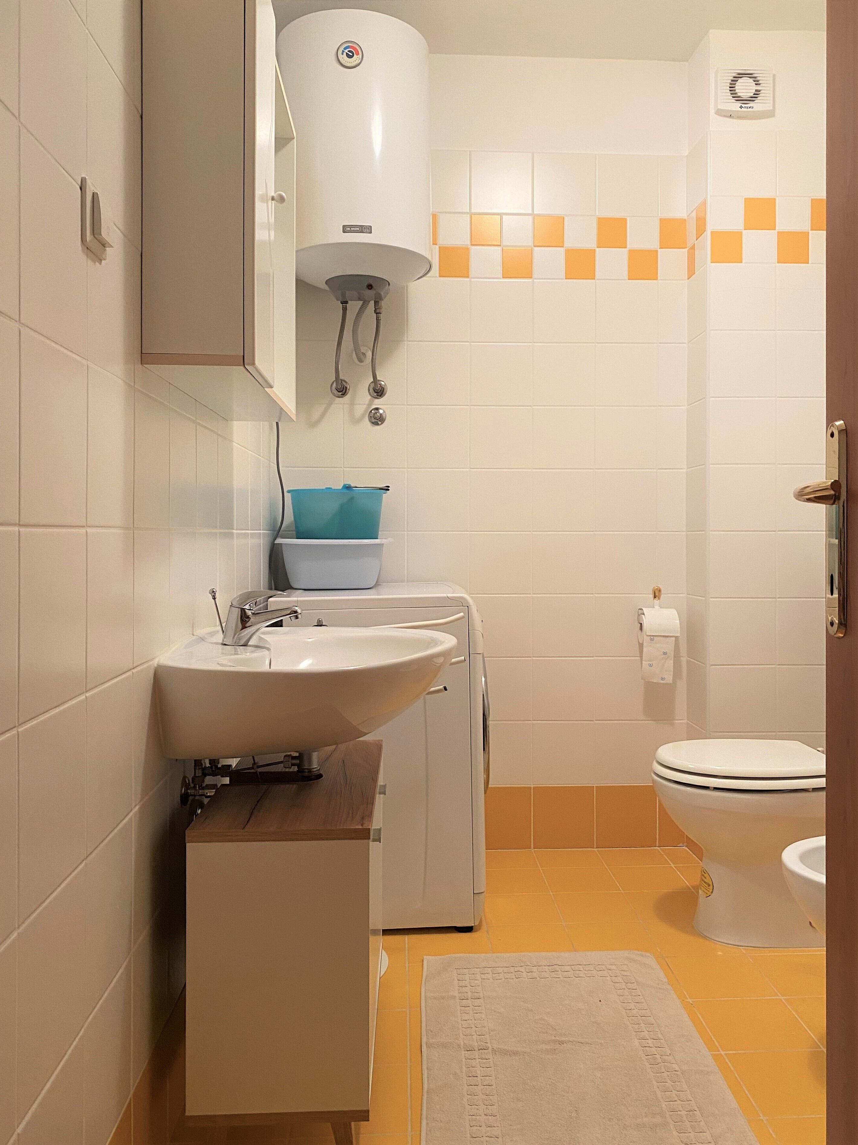 Un baño pequeño con lavamanos, inodoro y lavadora.