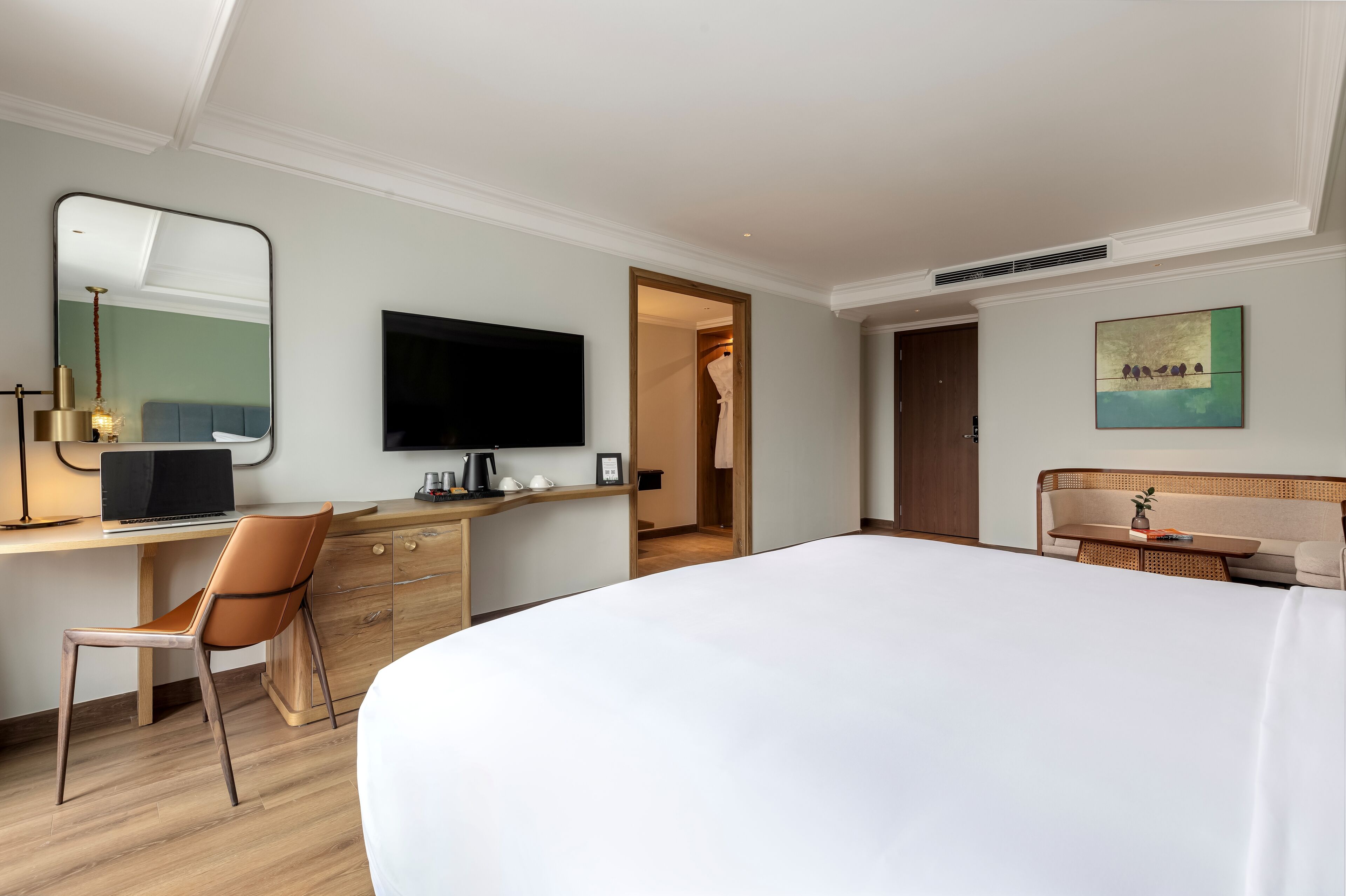 Une chambre d’hôtel avec un grand lit, un bureau avec une chaise, une télévision et un tableau au mur.