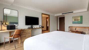 Une chambre d’hôtel avec un grand lit, un bureau avec une chaise, une télévision et un tableau au mur.