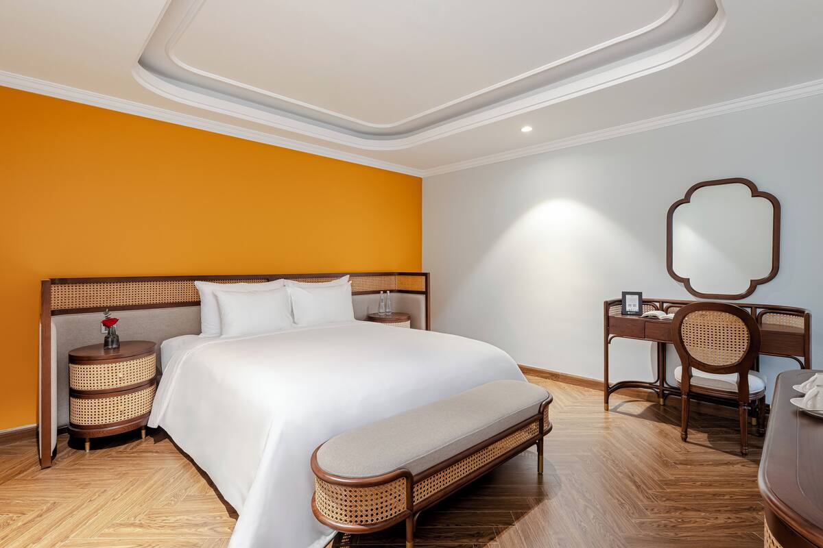 Une chambre d’hôtel avec un grand lit, une table de chevet, une chaise, un bureau et un miroir.