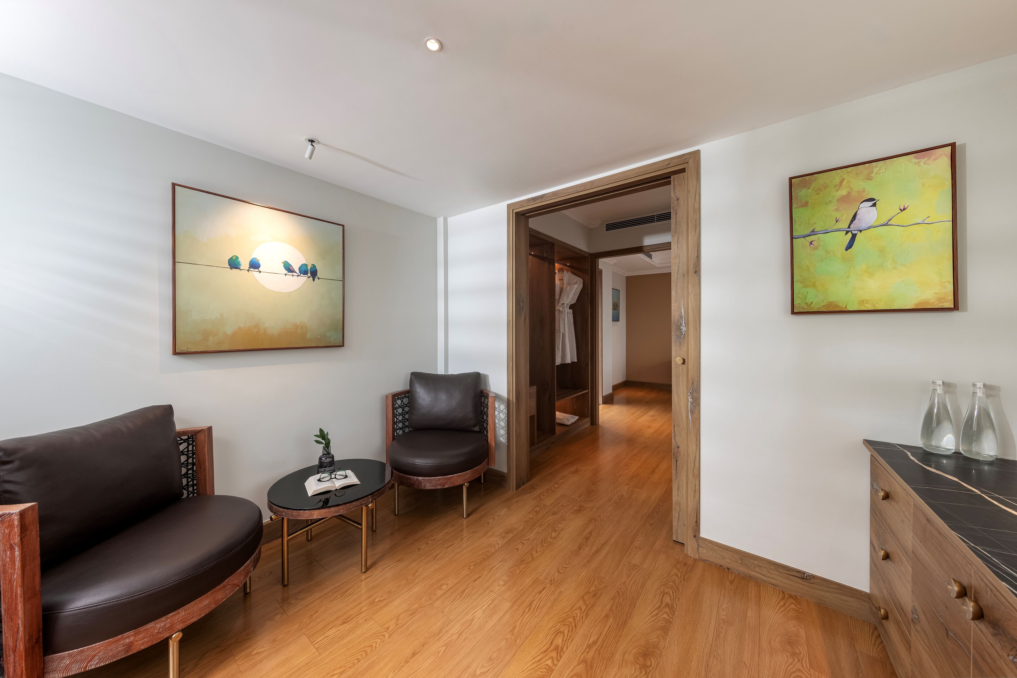 A modern living room with a sofa, a chair, a small table, and artwork on the walls.