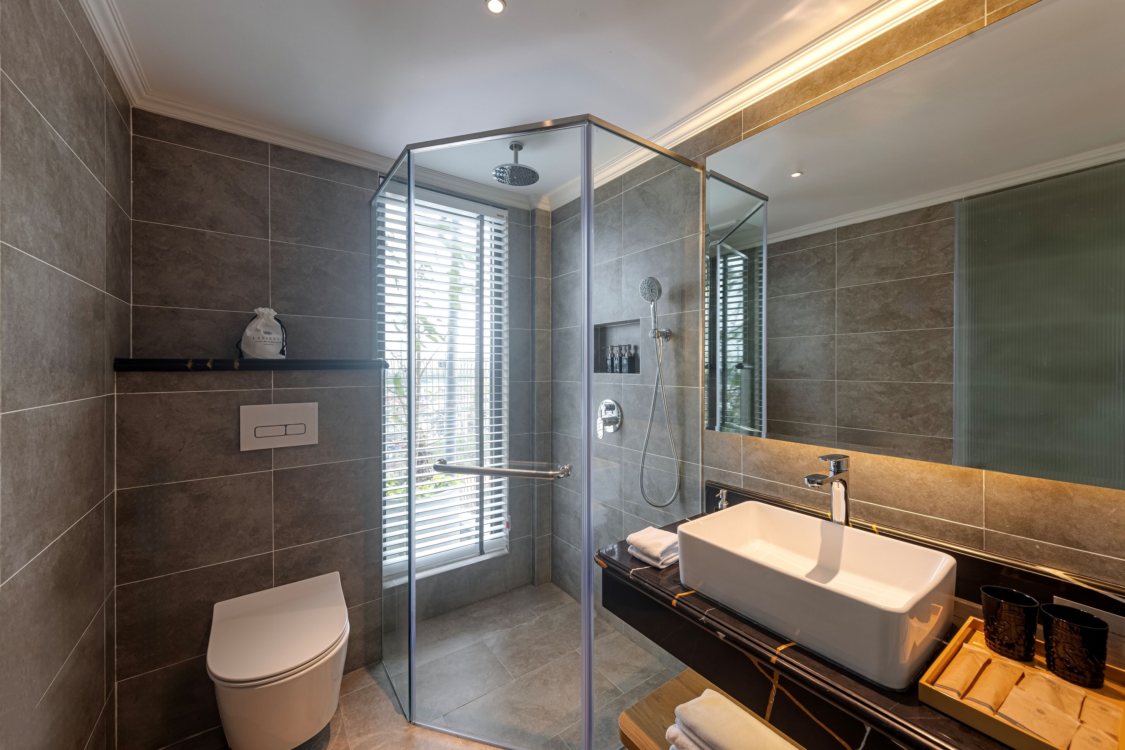 A modern bathroom with a glass-enclosed shower, a white sink, and a toilet.