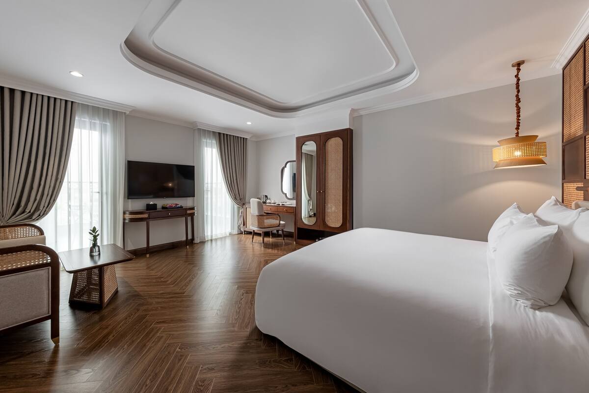 Une chambre d’hôtel moderne équipée d’un grand lit, d’un bureau, d’une télévision et d’un coin repas.