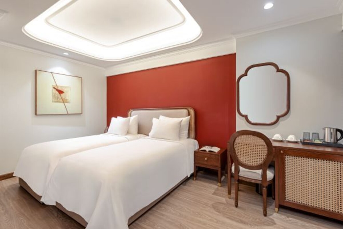 A hotel room with a bed, bedside tables, a desk, and a chair.