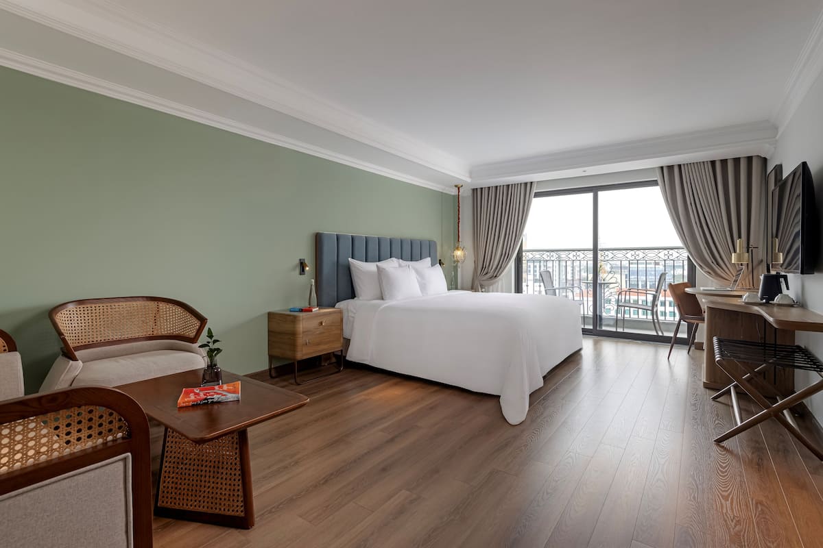 Une chambre d’hôtel avec un grand lit, un bureau, une chaise et un balcon avec vue.