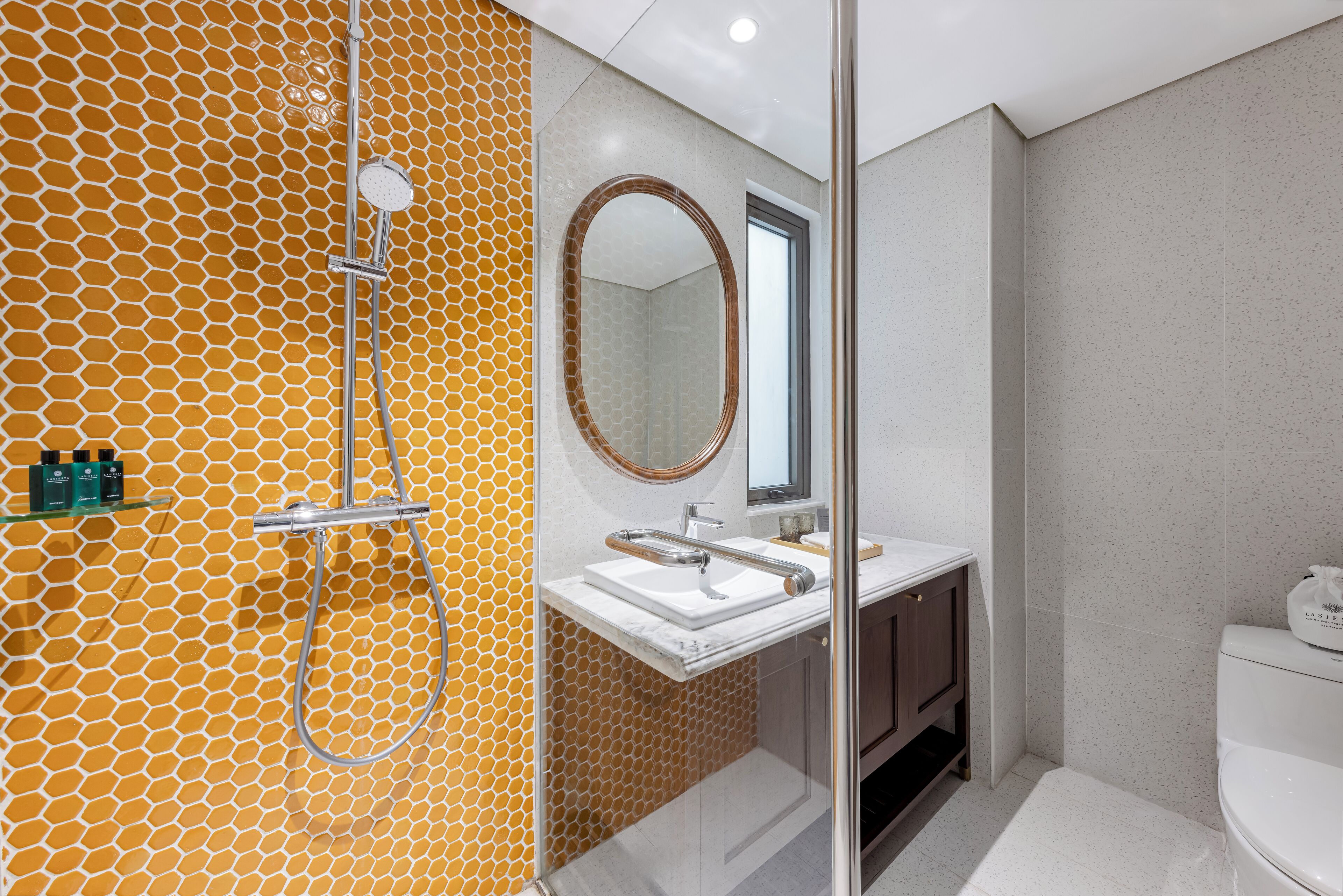 Ein Badezimmer mit Duschkabine aus Glas, einem weißen Waschbecken und einer Toilette.
