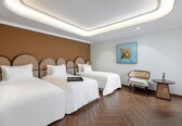 A hotel room with two beds, a wooden floor, a small round table, and a chair.
