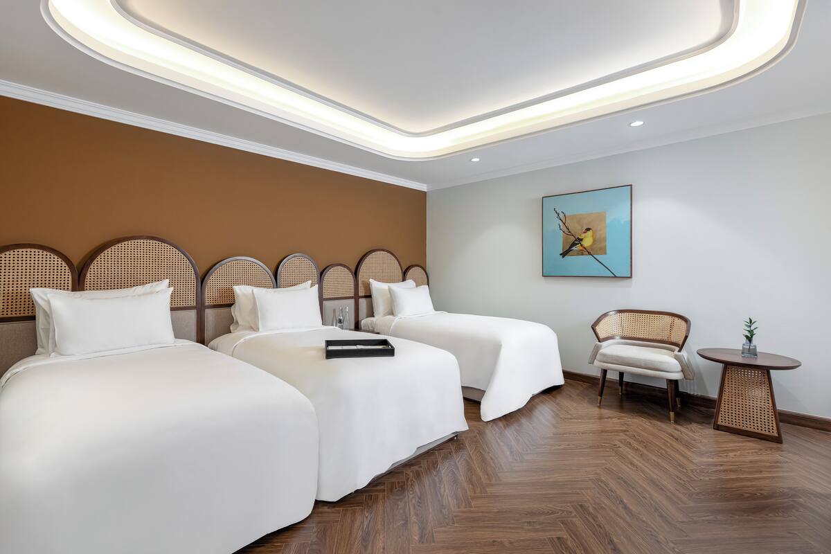 Une chambre d’hôtel avec deux lits, un plancher en bois, une petite table ronde et une chaise.