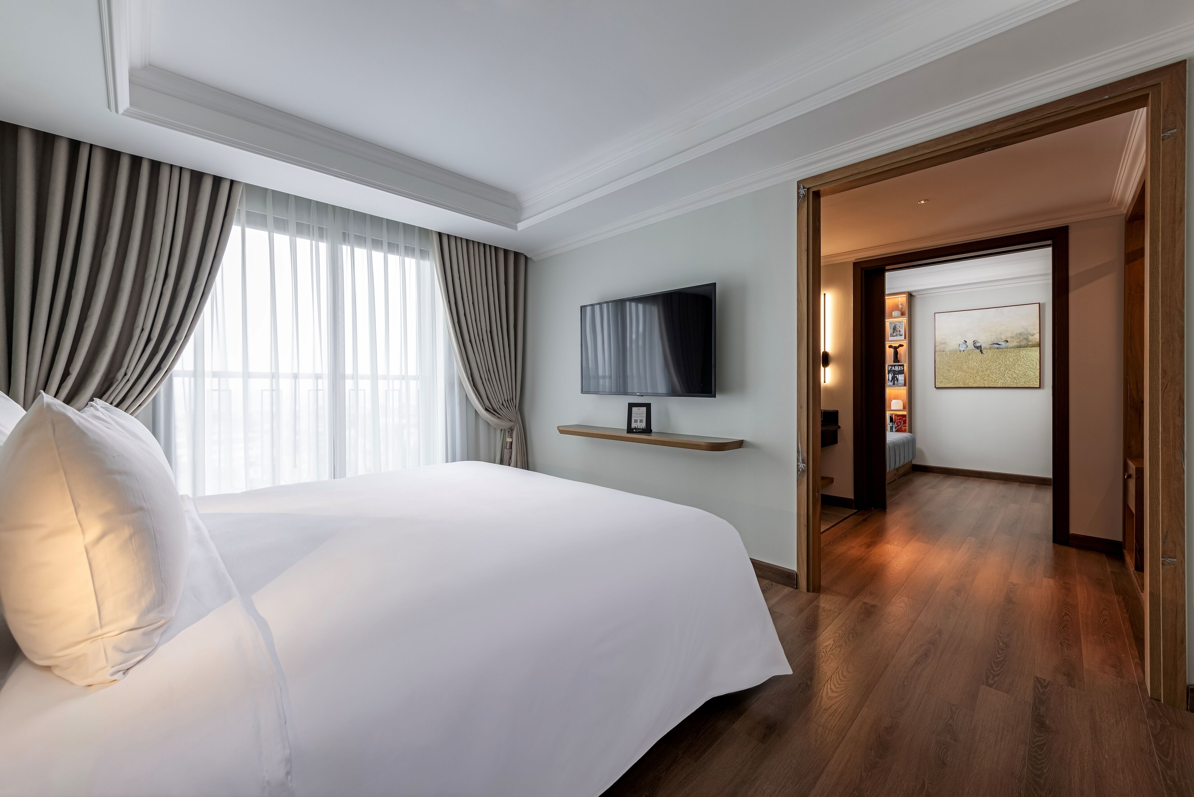 Habitación de hotel con una cama grande, un televisor de pantalla plana en la pared y piso de madera.