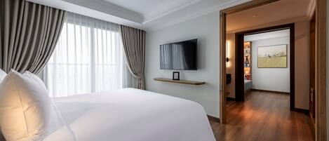 Habitación de hotel con una cama grande, un televisor de pantalla plana en la pared y piso de madera.