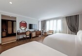 A hotel room with a large bed, a desk with a chair, a television, and a wardrobe.