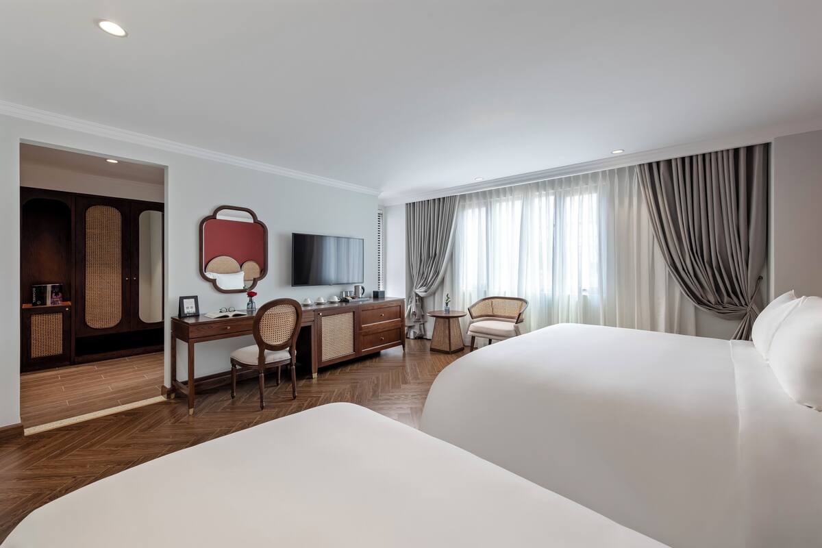 Une chambre d’hôtel avec un grand lit, un bureau avec une chaise, une télévision et une armoire.